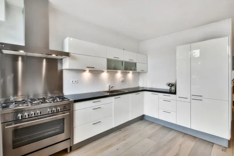 White high-gloss painted kitchen cabinets with dark countertop and stainless steel range | Color World Painting Charlotte